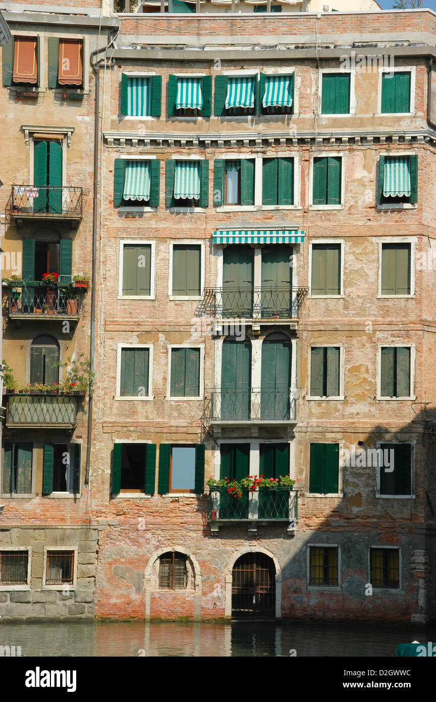 Symmetrische Fassade eine Canalside Gebäude in Venedig mit grünen Fensterläden und gestreiften Markisen Stockfoto