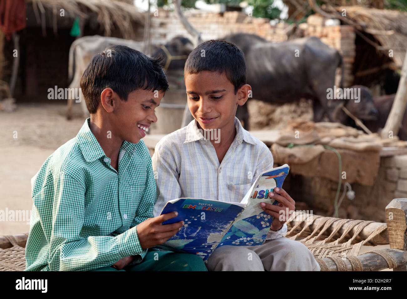 Indien, Uttar Pradesh, Agra, Kind in Schuluniform und Bruder in ungleichmäßigen Teilen Englisch Lehrbuch Stockfoto