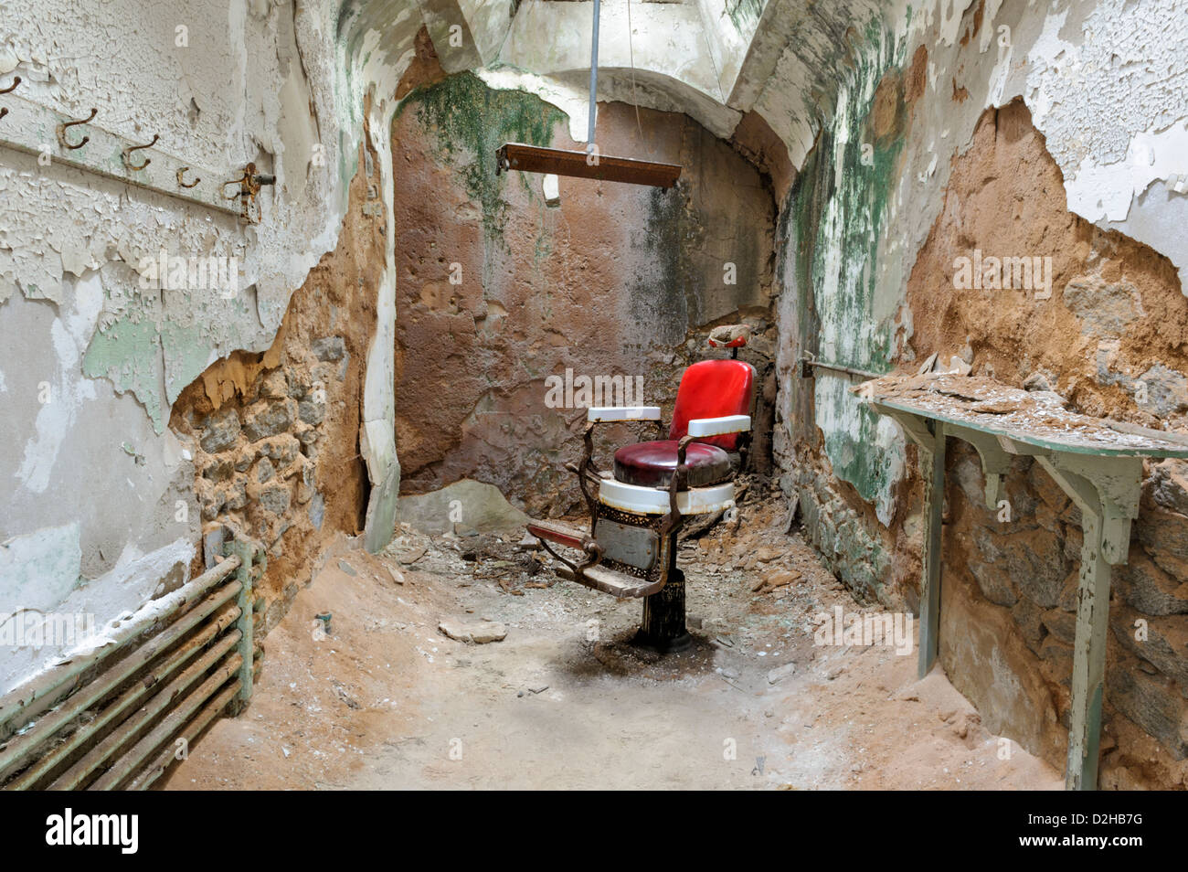 Friseur-Stuhl in verfallenden Gefängniszelle, unheimlichen Ruinen von haunted Eastern State Penitentiary, Philadelphia, PA, USA. Stockfoto