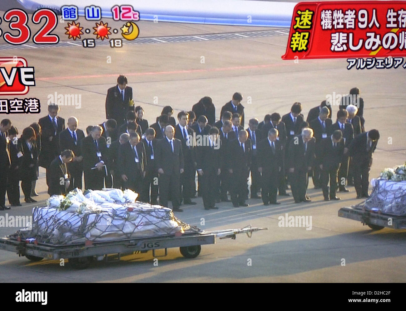 Auf diesem Foto genommen von live-Aufnahmen im japanischen Fernsehen ausgestrahlt beugen trauernden ihre Köpfe als die Leichen von neun der 10 japanischen bestätigt tot nach der Belagerung als Geisel in Algerien Weg von einem Flugzeug auf dem internationalen Flughafen in Tokio am 25. Januar 2013 rollte sind.  Die staatliche Ebene, die kurz nach 07:00 am aufsetzten, trug auch sieben japanische Überlebenden von der Belagerung. Foto: Robert Gilhooly Stockfoto