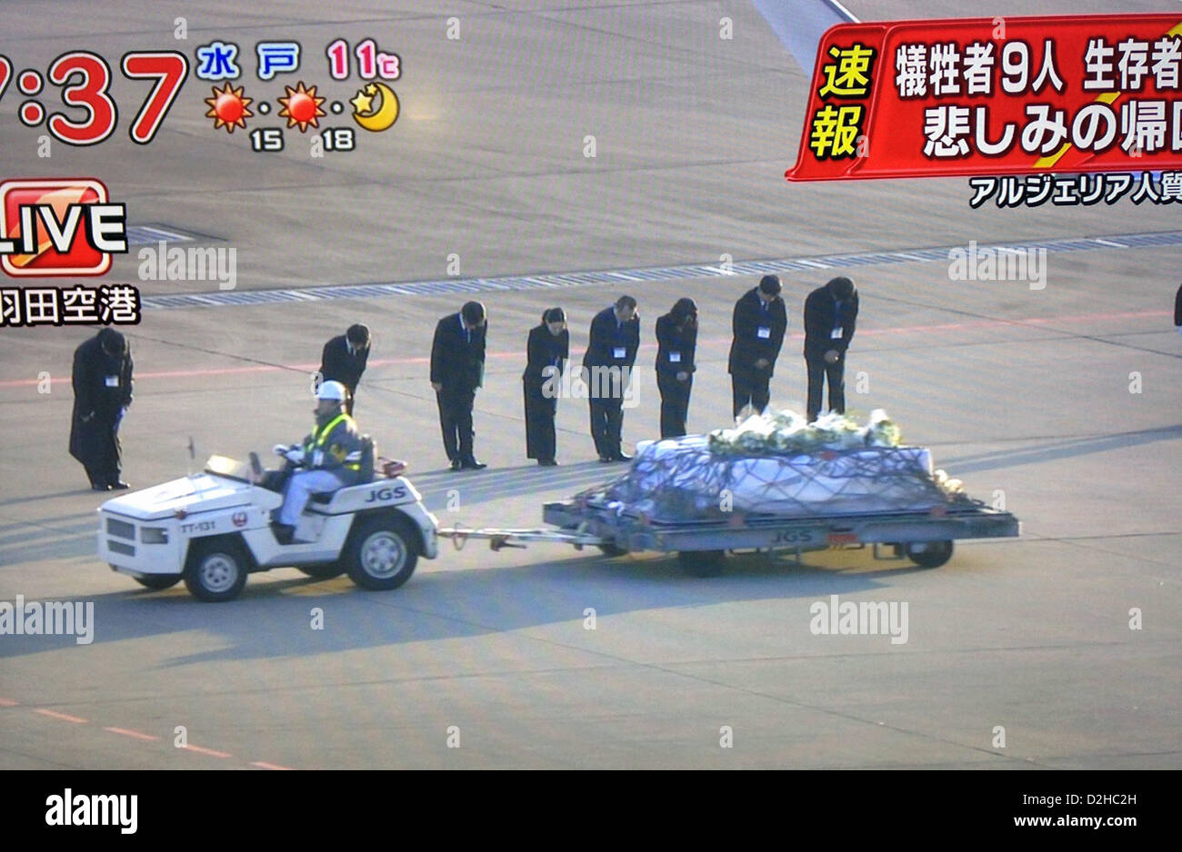 Auf diesem Foto genommen von live-Aufnahmen im japanischen Fernsehen ausgestrahlt beugen trauernden ihre Köpfe als die Leichen von neun der 10 japanischen bestätigt tot nach der Belagerung als Geisel in Algerien Weg von einem Flugzeug auf dem internationalen Flughafen in Tokio am 25. Januar 2013 rollte sind.  Die staatliche Ebene, die kurz nach 07:00 am aufsetzten, trug auch sieben japanische Überlebenden von der Belagerung. Foto: Robert Gilhooly Stockfoto