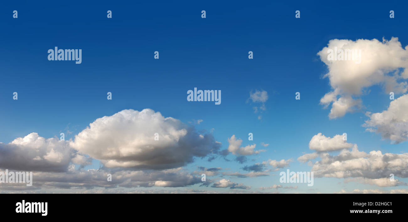 Blauer Himmel mit mehreren weißen Cumuluswolken am späten Nachmittag. Cinema-Scope-Format. Stockfoto