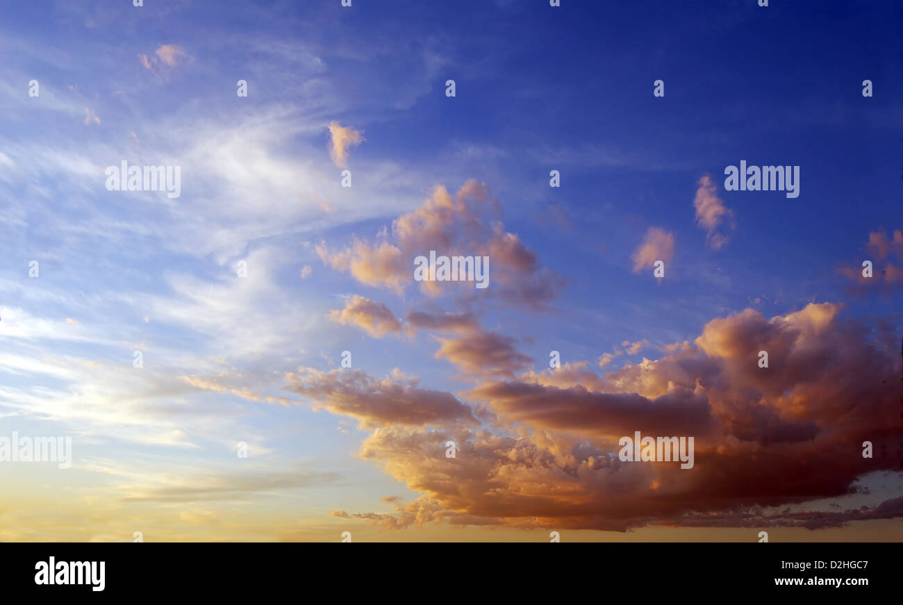 Blauer Himmel, Sonnenuntergang Zeit nähert sich mit flauschigen Wolken in Orange getönt. Stockfoto