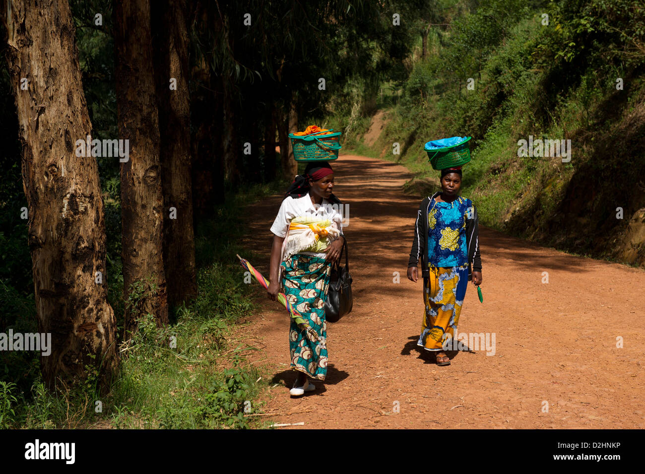 Frauen, die Körbe auf dem Kopf zu Fuß entlang der Straße, Ruanda Stockfoto