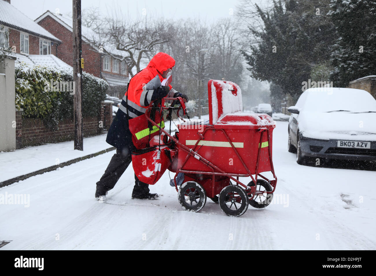 Der Postbote liefert die Post bei Schneefall. Stockfoto