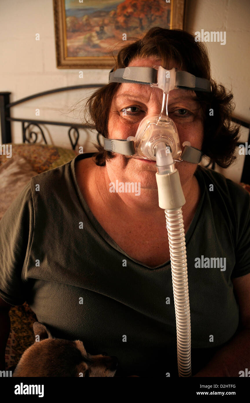 Ein chronisch kranker Patient gilt eine Bi-Pap-Maschine, die kontinuierlich Luft liefert während des Schlafes für die Behandlung von Schlafapnoe. Stockfoto