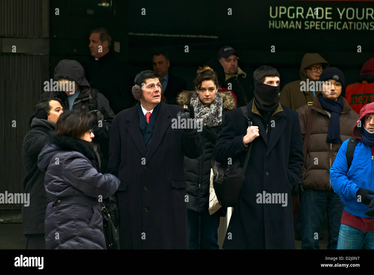 New York, USA. 25. Januar 2013.  An einem Eingang zu Pennsylvania Station bündeln Menschen für einen weiteren Tag der Temperaturen unter dem Gefrierpunkt wie New York einen schweren Kälteeinbruch erträgt.  Eine Anzeige im Hintergrund liest, Ihren menschlichen Vorgaben "upgrade". Bildnachweis: Joseph Reid / Alamy Live News Stockfoto