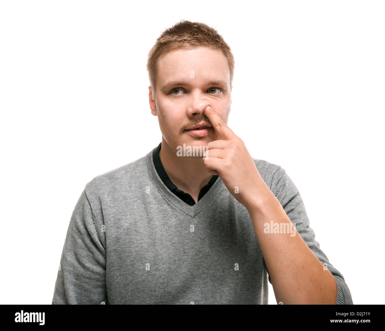 Lustiger Kerl sammeln seine Nase... Humorvolles Porträt eines jungen Mannes konzentriert sich bei der Auswahl seiner Nase. Stockfoto
