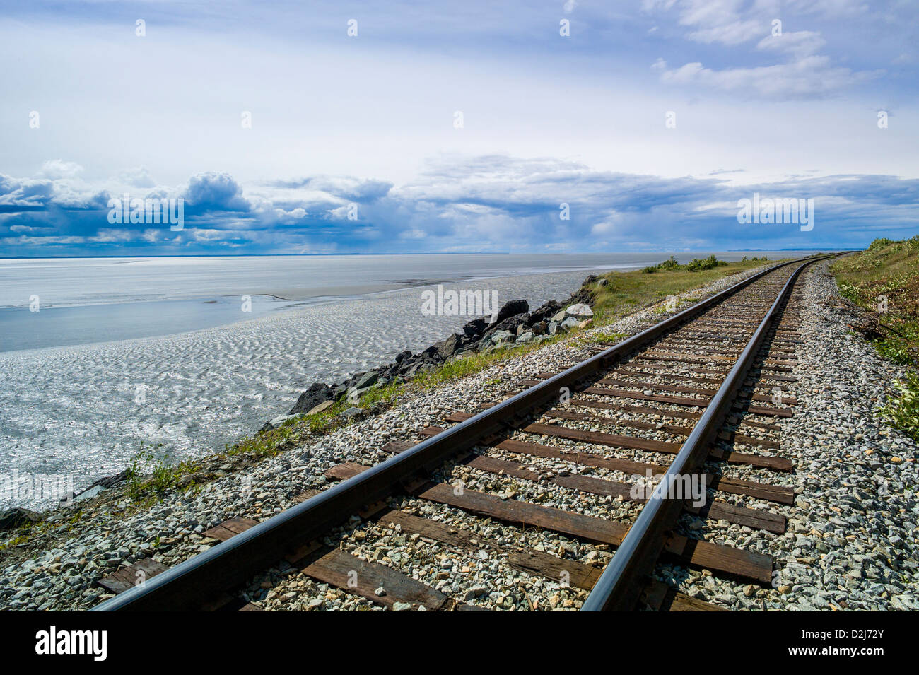 Eisenbahnschienen säumen die zerklüftete Landschaft von Meer und Bergen, Turnagain Arm, südlich von Anchorage, Alaska, USA Stockfoto