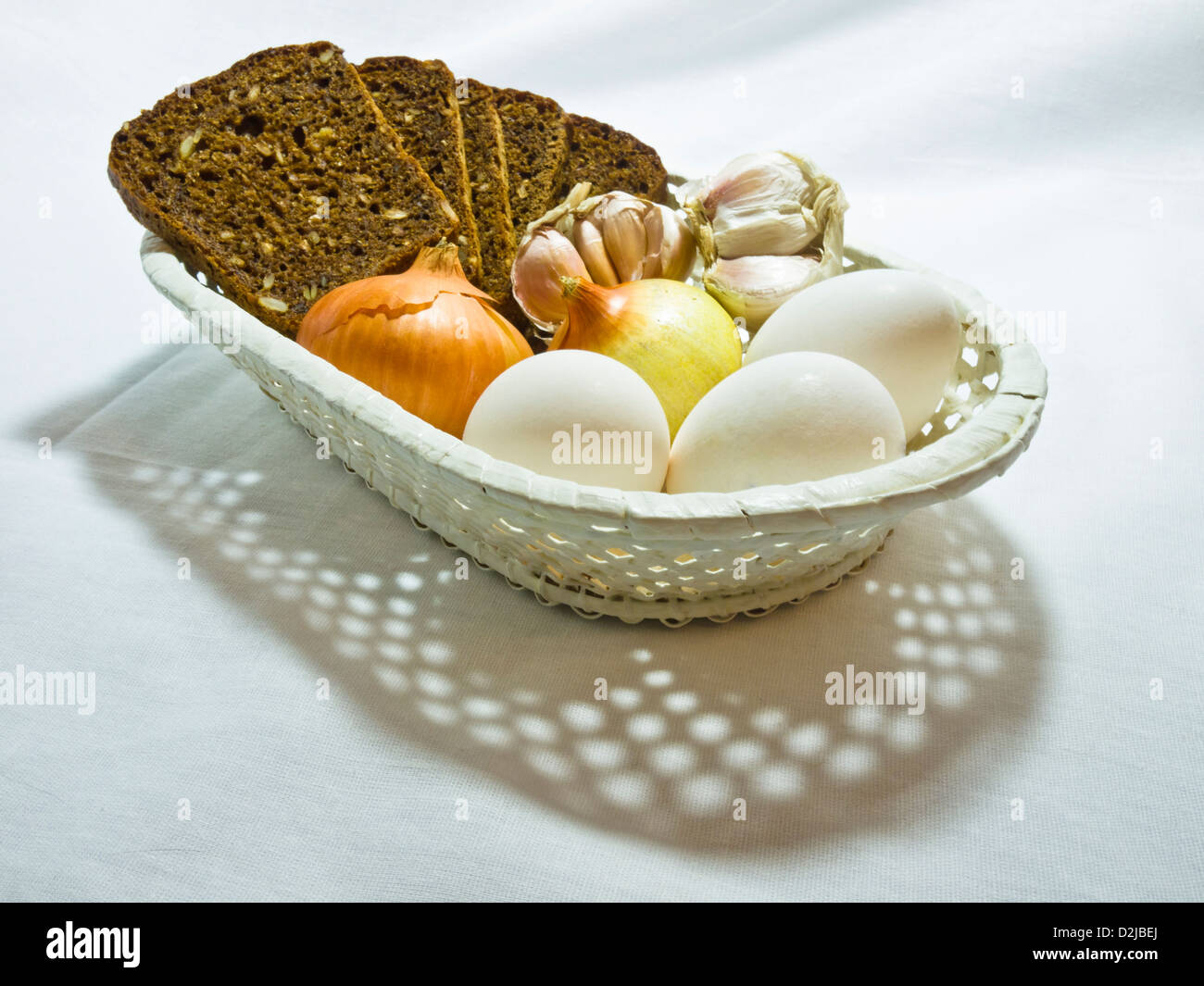 Käse, Eiern, Zwiebel und Knoblauch in einem weißen Wum-Korb Stockfoto