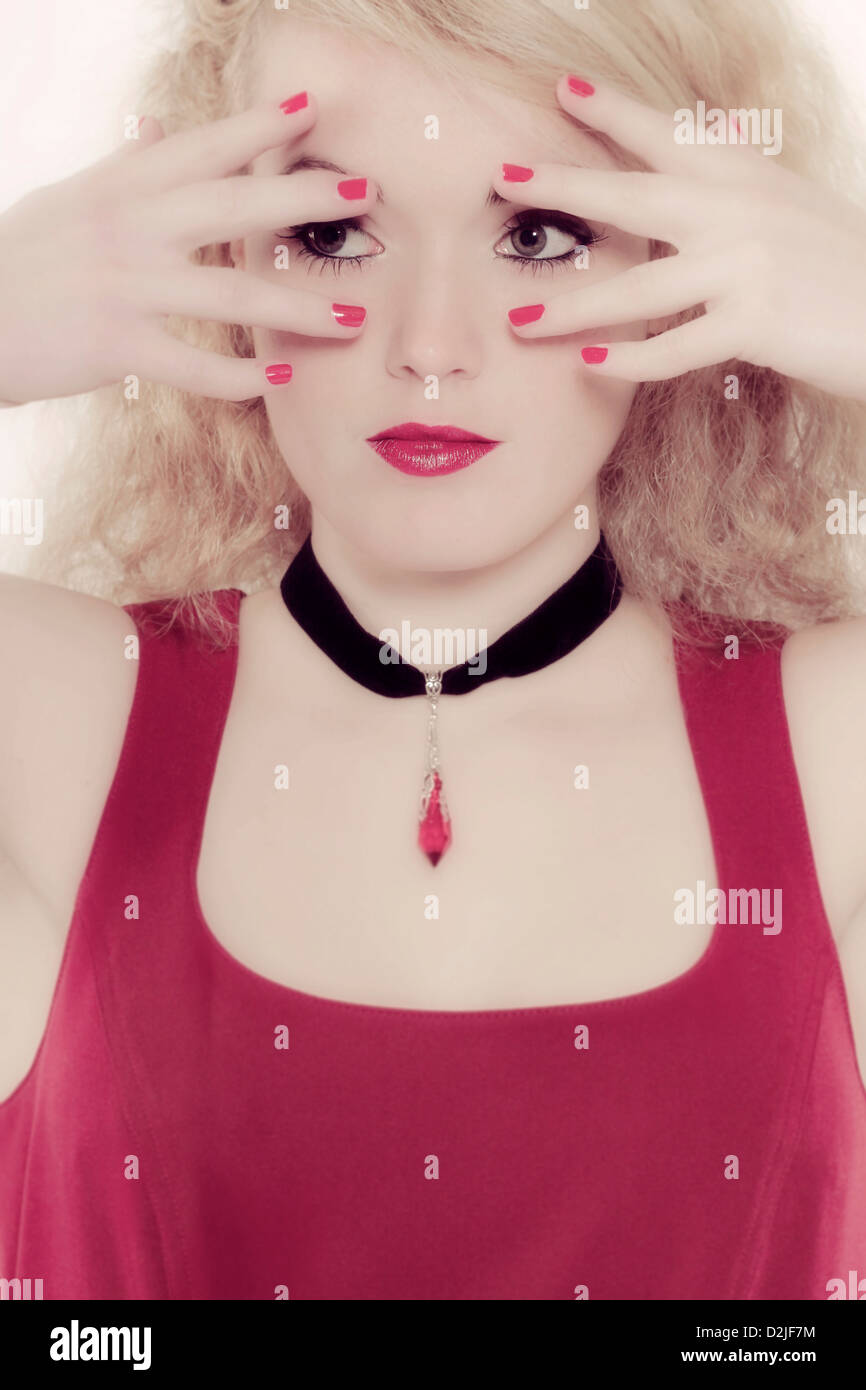 eine Mädchen sucht durch ihre Finger Stockfoto