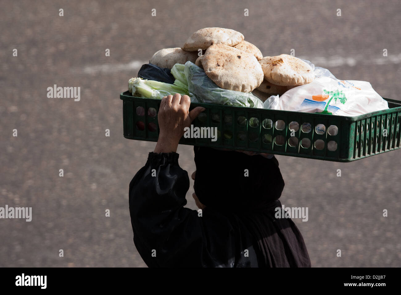 Kairo, Ägypten, trägt verschleierte alte Frau ihr Einkaufen auf dem Kopf Stockfoto