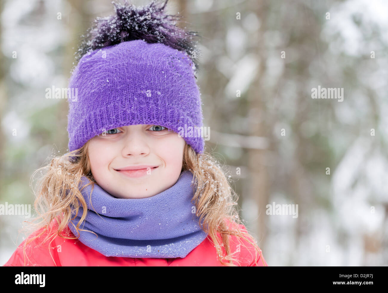 Schöne blonde Mädchen im Winter Oberbekleidung mit Schneeflocken über Wald-Hintergrund Stockfoto