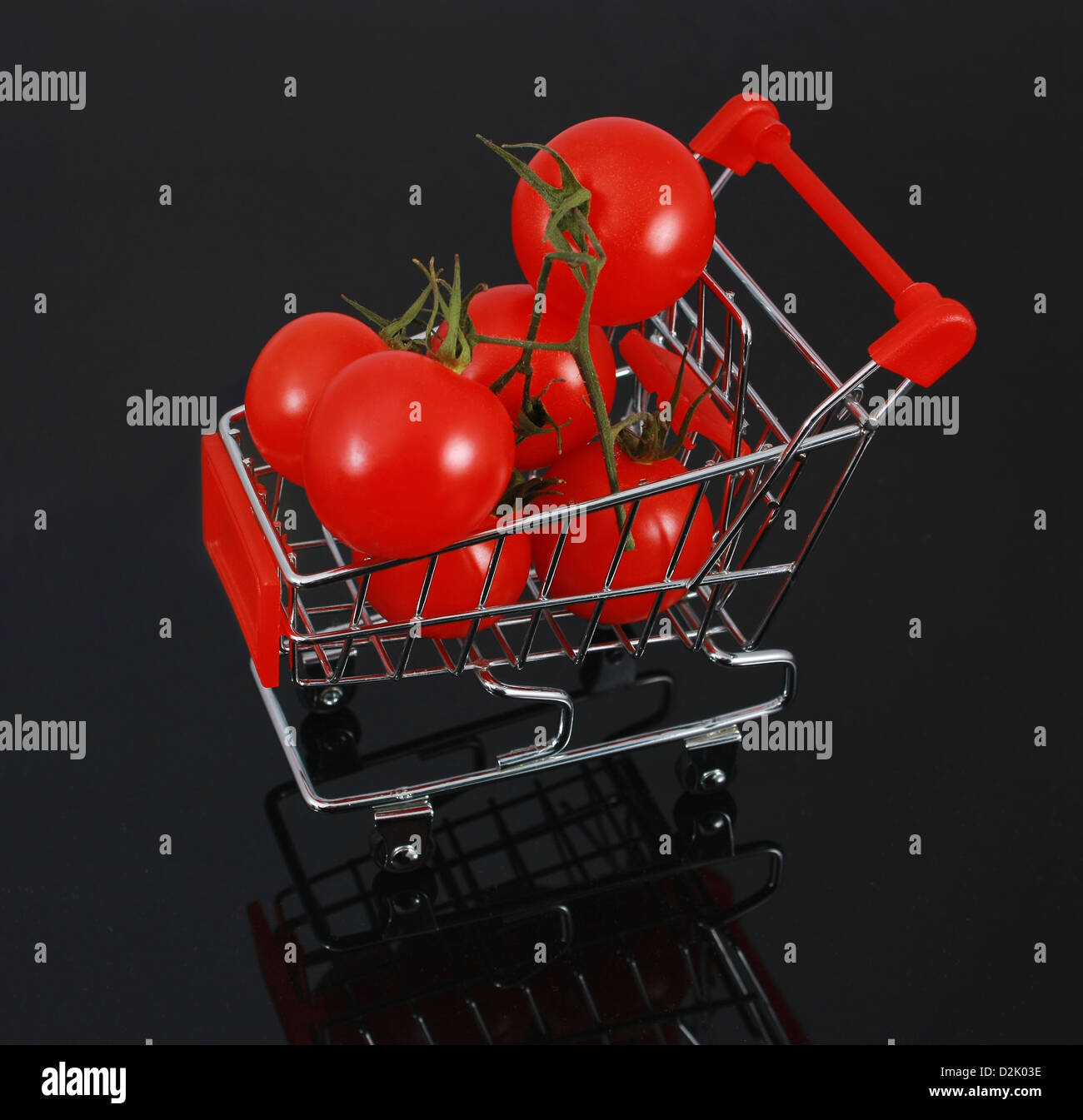 Bio-Tomaten im kleinen Warenkorb auf Reflexion auf schwarzem Hintergrund isoliert Stockfoto