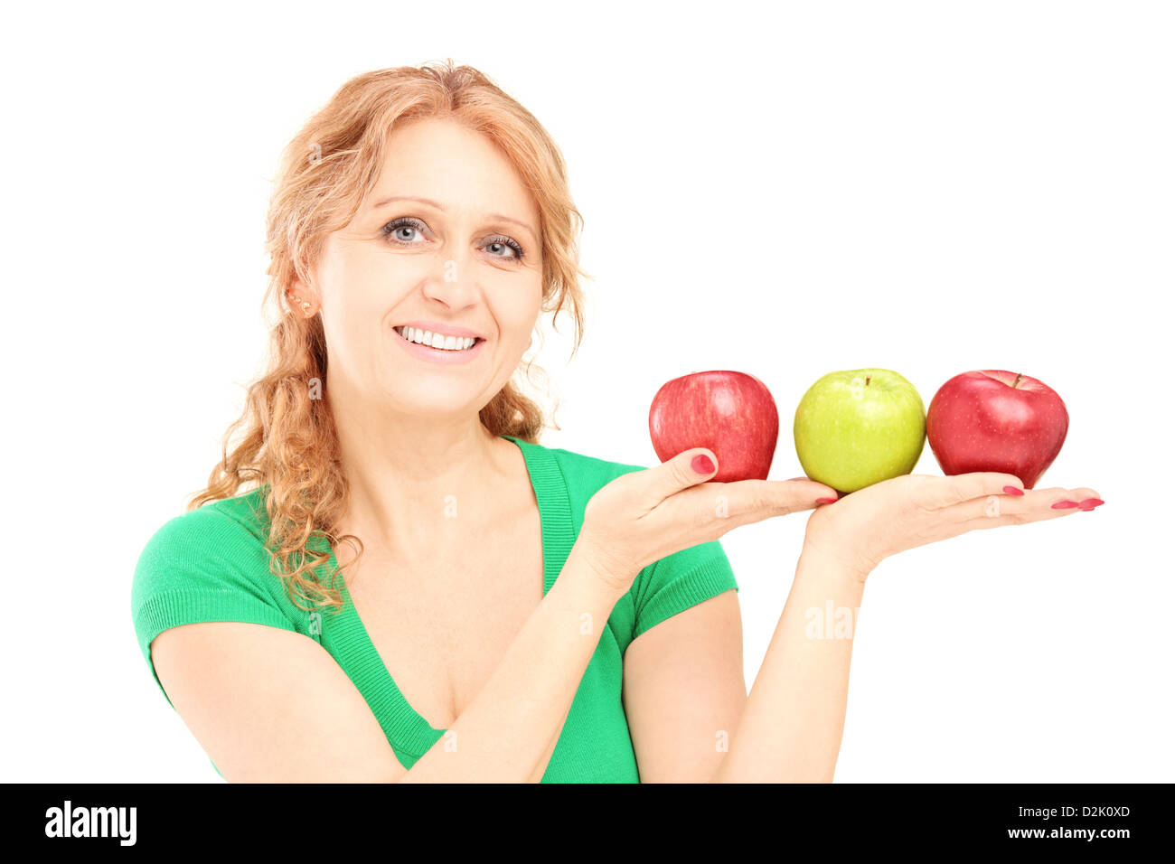 Reife schöne Frau sitzt und hält drei Äpfel isoliert auf weißem Hintergrund Stockfoto