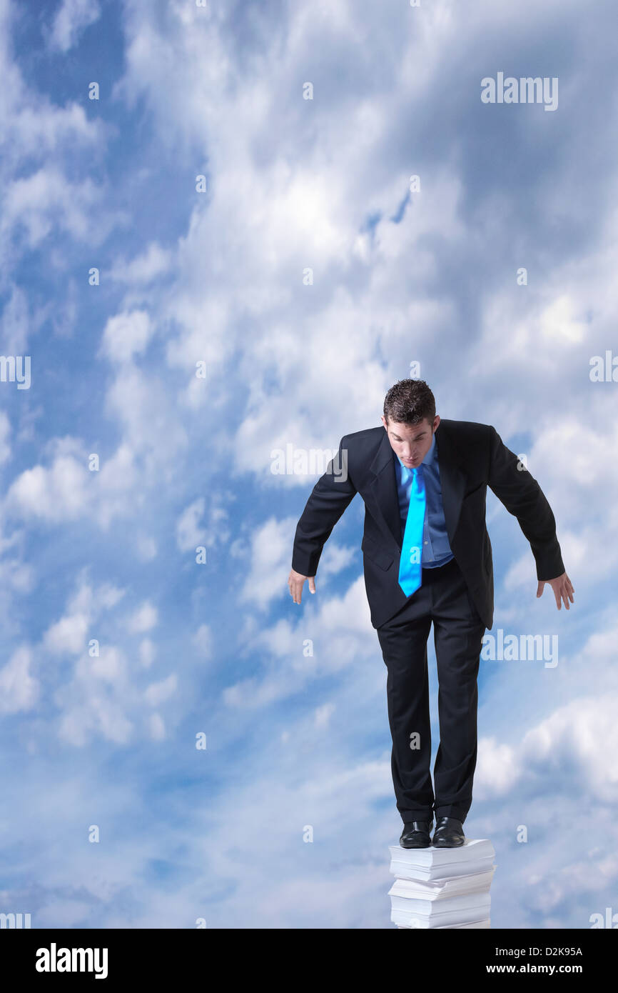 Geschäftsmann, stehend auf einem großen Stapel Papier nach rechts oben in den Himmel Stockfoto