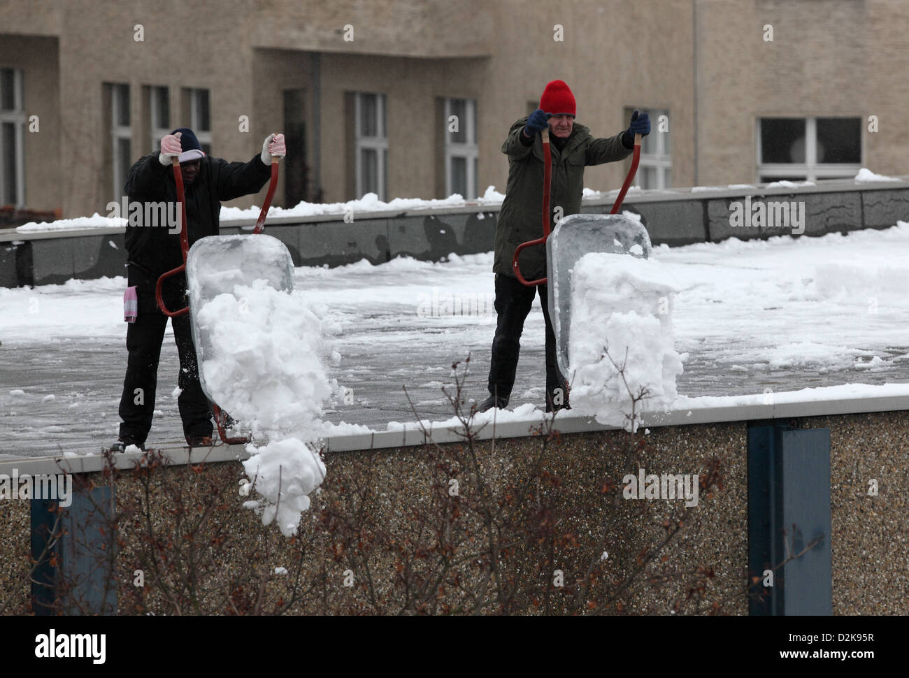 Berlin, Deutschland, Männer entfernen Schnee von einem Flachdach Stockfoto