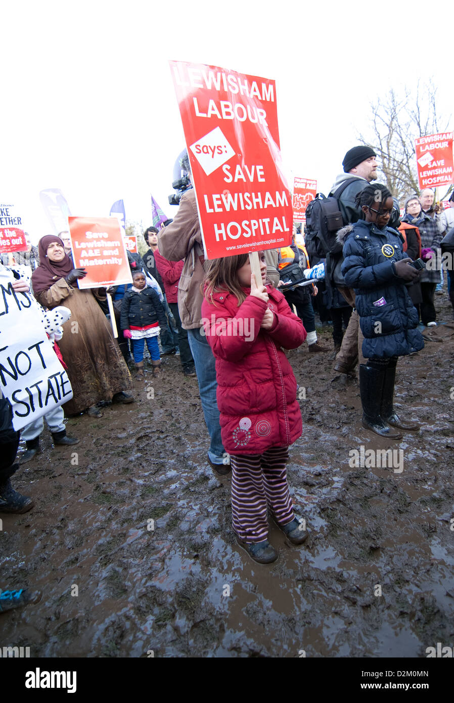 Junge Mädchen steht, hält ein Plakat in den schlammigen Bedingungen am Mountfield Park während speichern Lewisham Krankenhaus demo Stockfoto