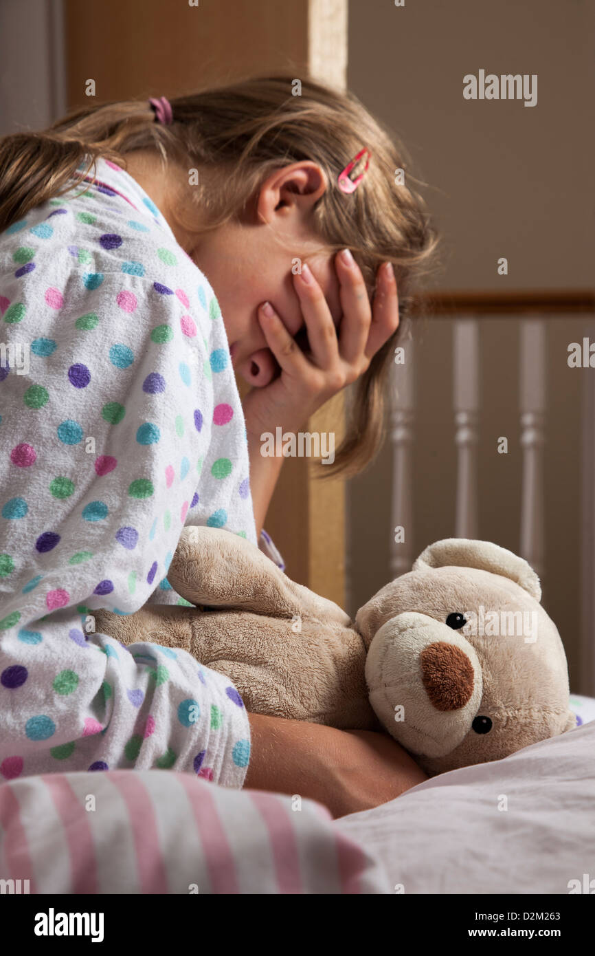 Junge weibliche hand trägt einen Schlafanzug umklammert ihr Teddy Bär, bedeckte ihr Gesicht. Stockfoto