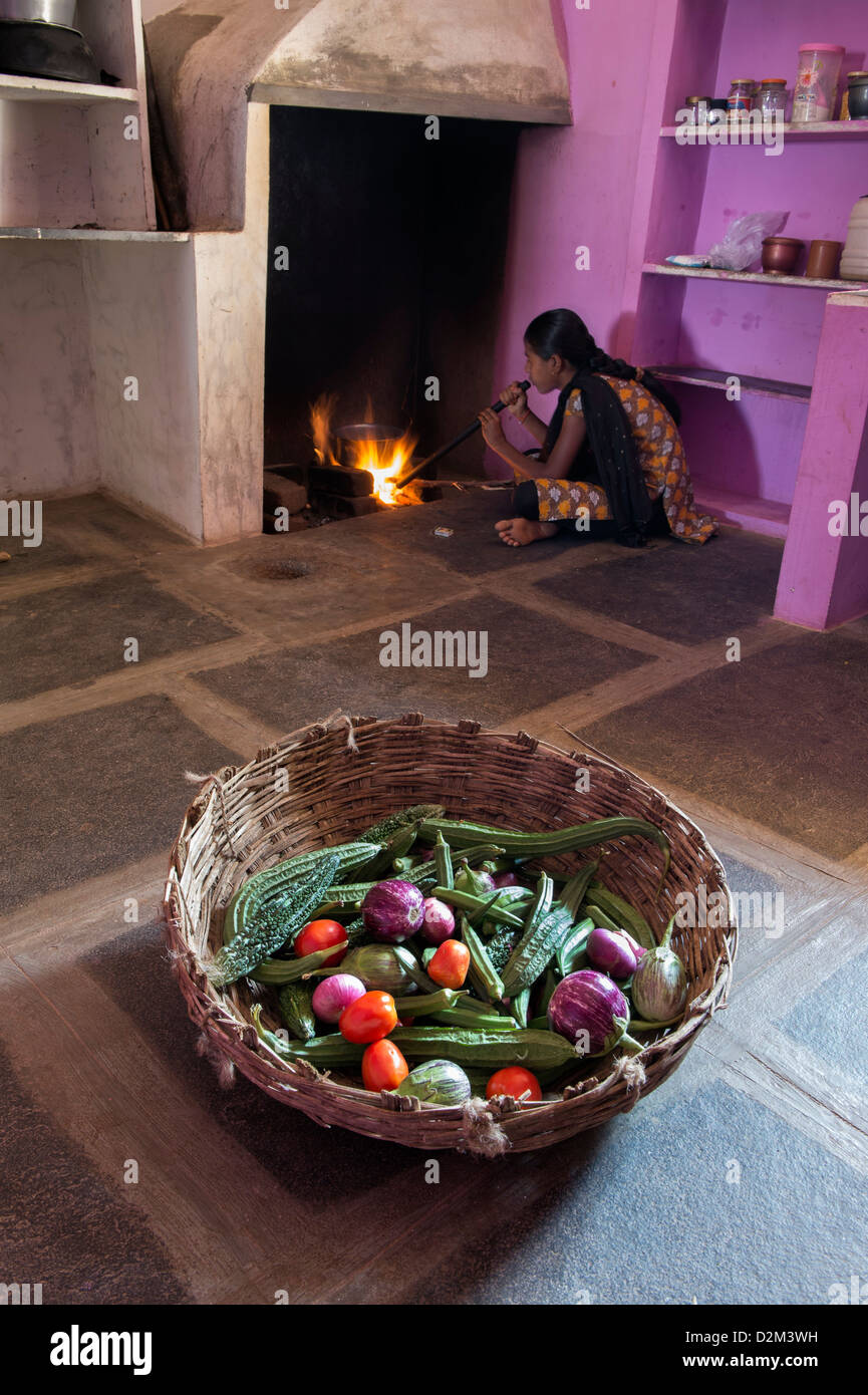 Korb mit indischen Gemüse und ein Mädchen, das Feuer in der Küche von einem indischen Dorfhaus vorbereiten. Andhra Pradesh, Indien Stockfoto