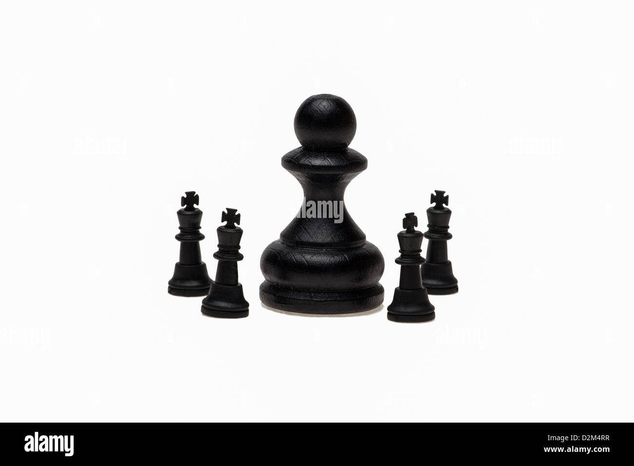 Neuer Chef. Eine große schwarze Schachfigur und vier kleine schwarze Schach-Könige. Stockfoto