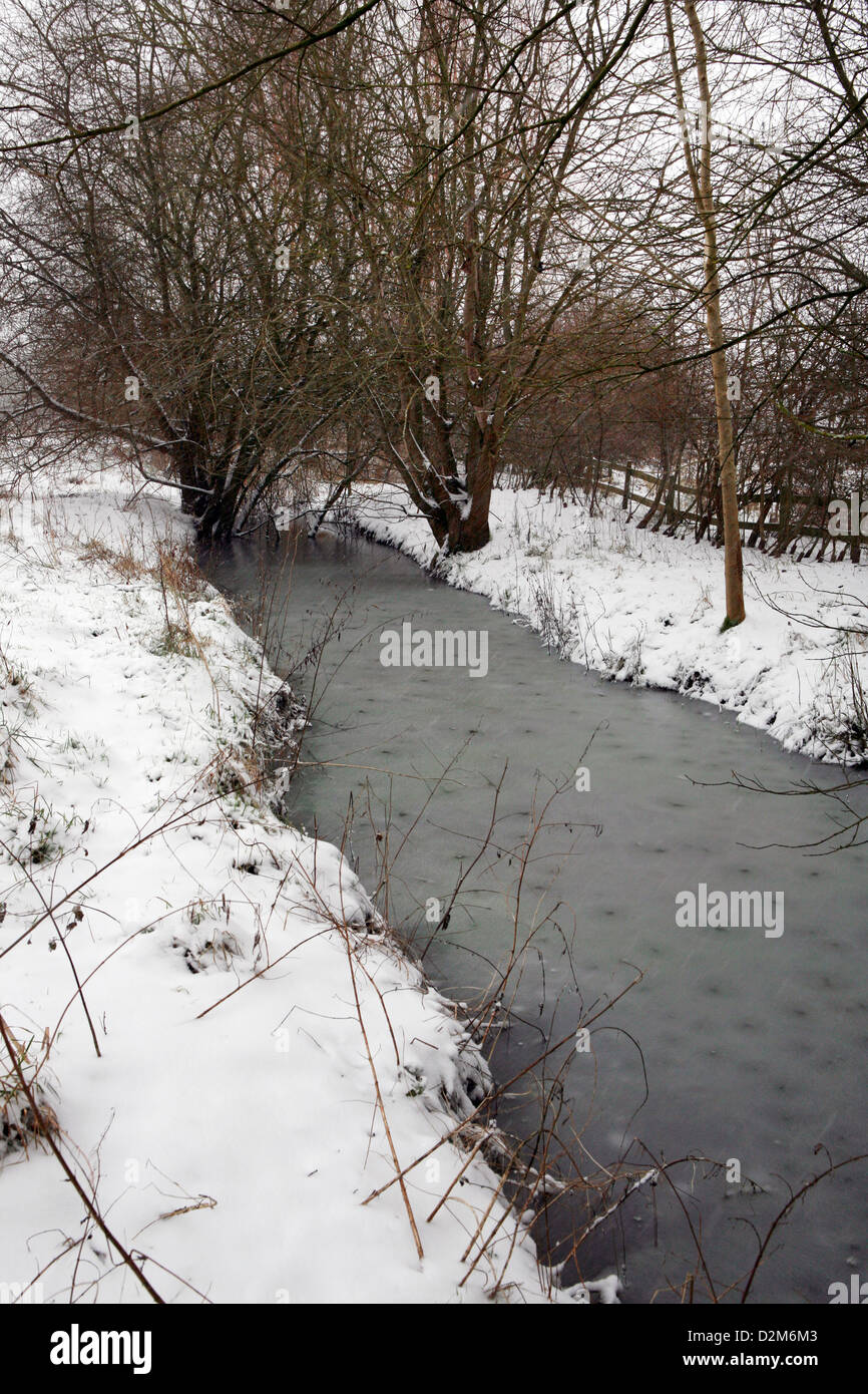 Gefrorenes Graben Wasser in einer Flussaue, Kidlington, Oxfordshire, England. Schnee fällt und liegt auf dem Boden. Stockfoto