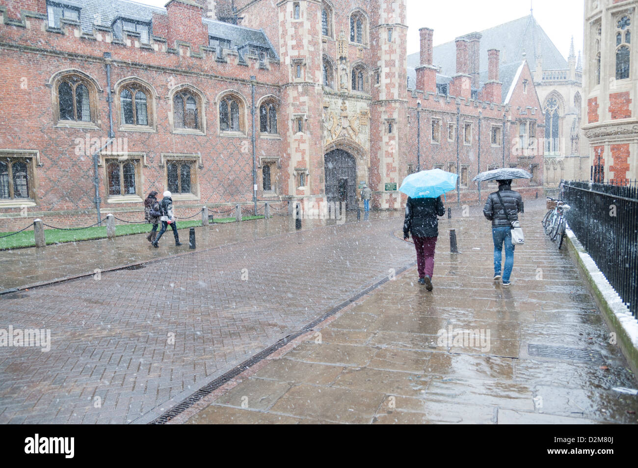 Menschen wandern im verschneiten schlechtes Wetter in St. John's Street Cambridge UK tragen Regenschirme in der Nähe von Str. Johns Hochschule Stockfoto