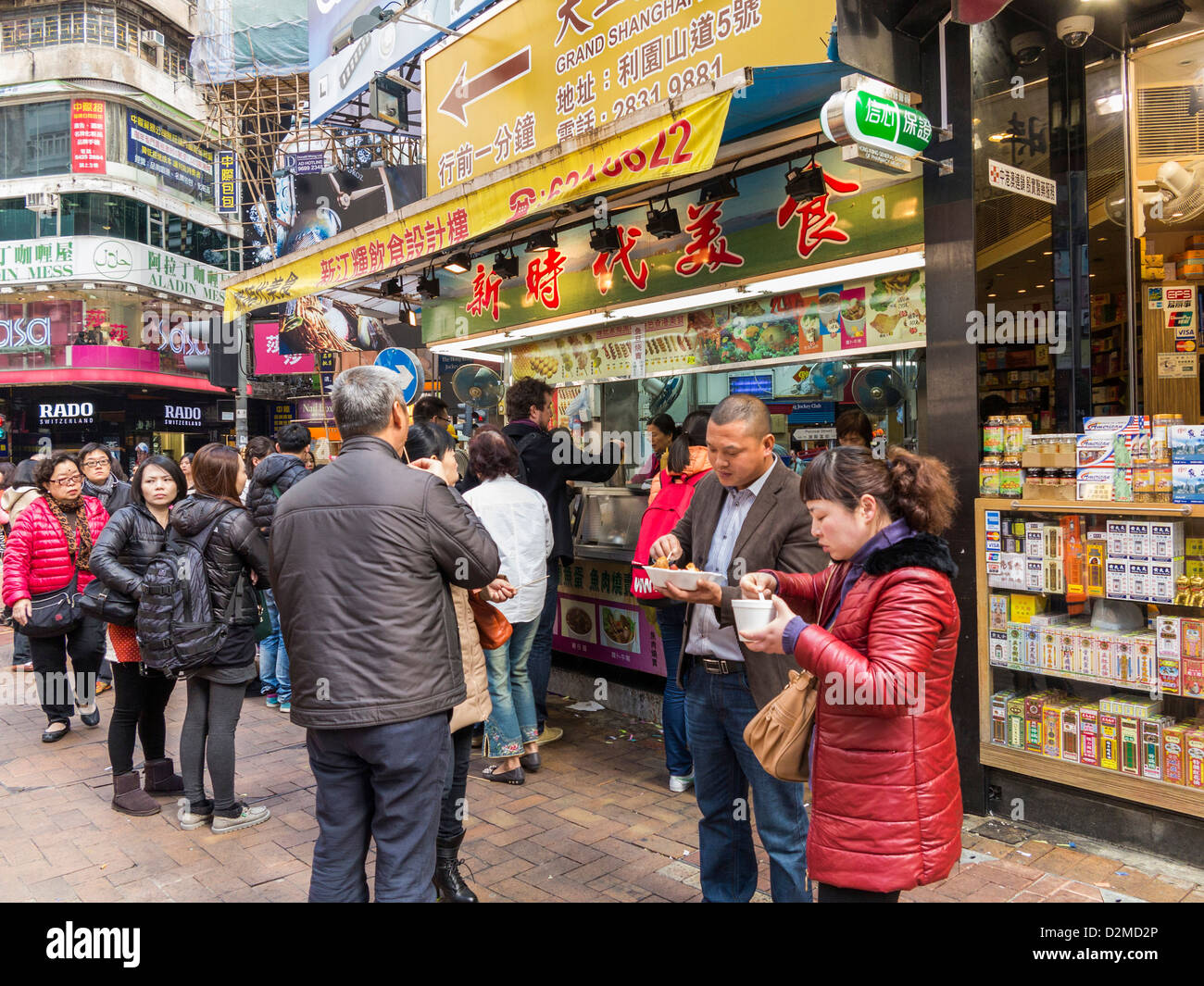 Hong Kong Street Food - geschäftiger Verkaufsstand, an dem Hongkongs berühmte Ei-Waffeln verkauft werden, während die Leute in der Warteschlange stehen und essen Stockfoto