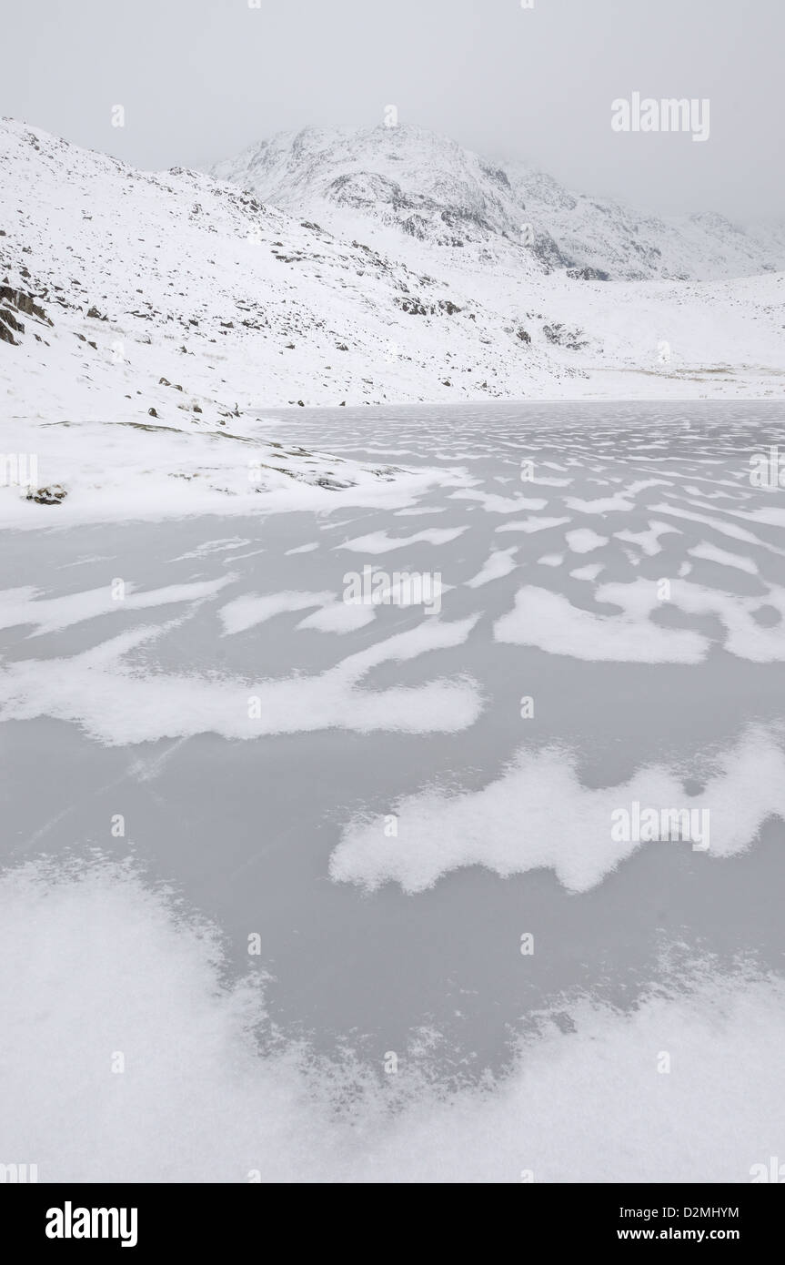 Eis-Muster auf gefrorene landschaftlich Tarn mit großen Ende im Hintergrund. Winter-Bergblick im englischen Lake District Stockfoto