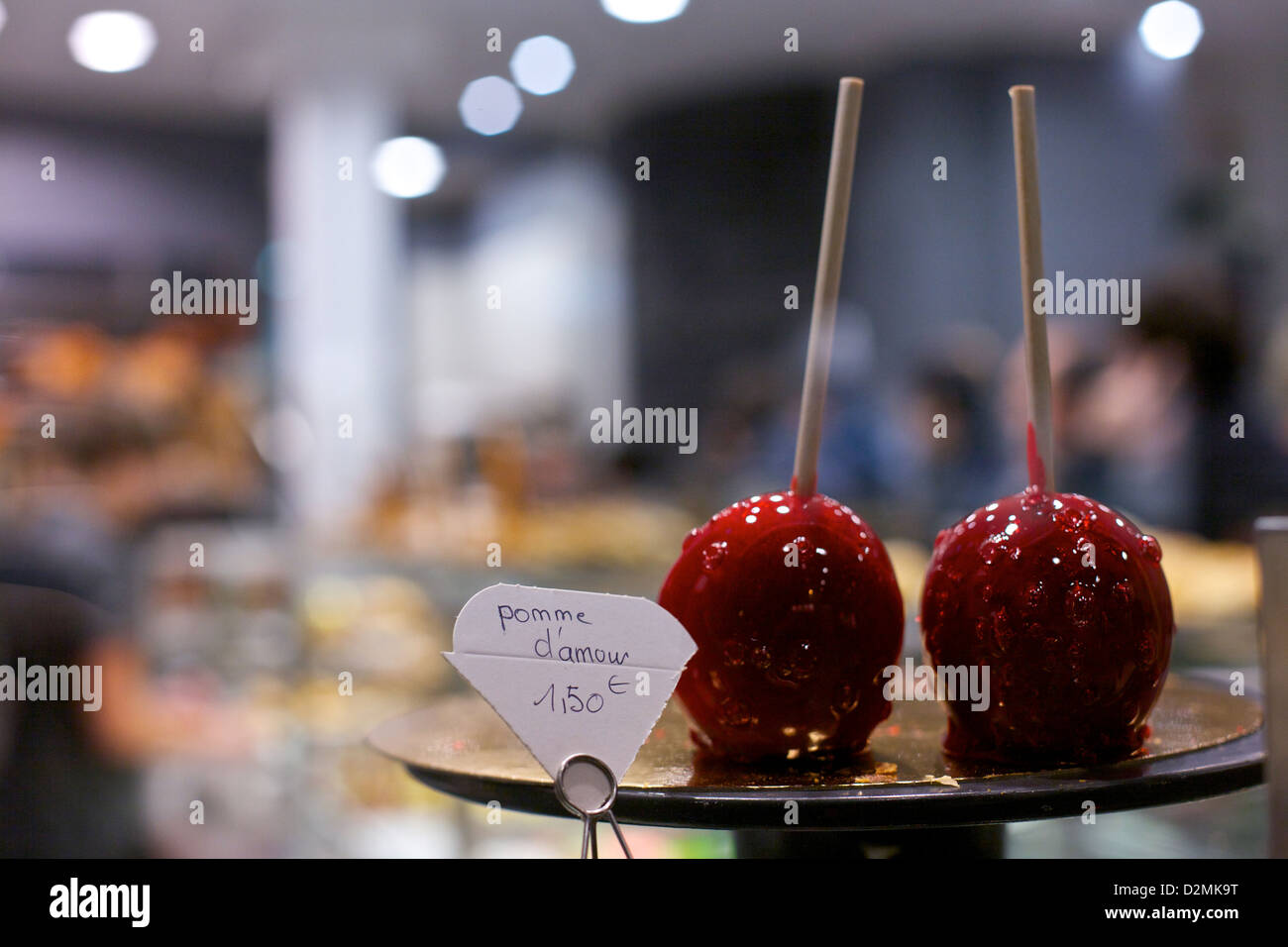 Liebesäpfel, bekannt als Pommes d ' Amour oder Äpfel der Liebe, sitzen in einem Bonbon-Schaufenster in Paris, Frankreich Stockfoto