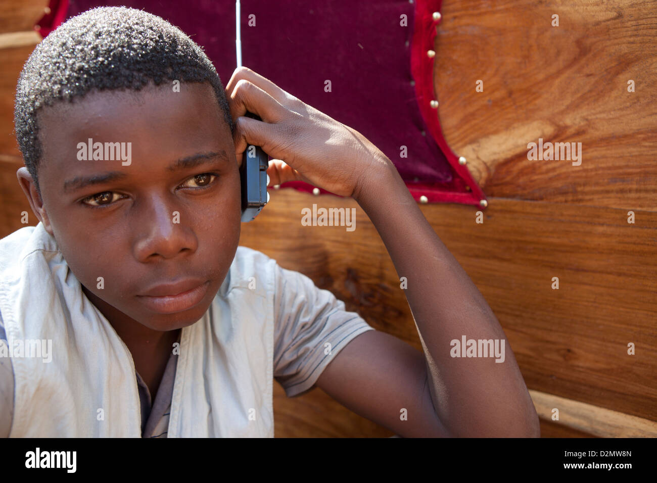 NAMPULA, Mosambik, Mai 2010: Sonntagsmarkt - hört ein Junge auf seinem Radio während der Arbeit an einem Stand auf dem Möbelmarkt. Stockfoto