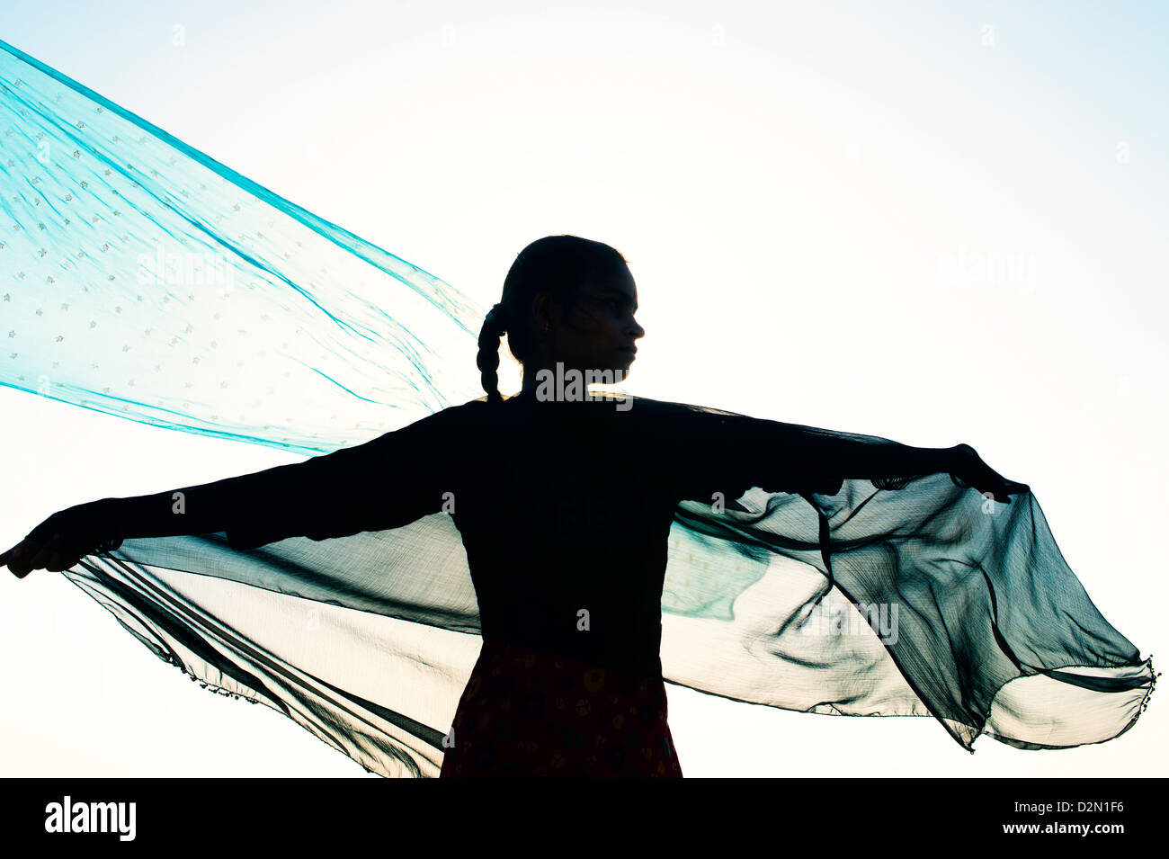 Indische Mädchen mit Schleier im Wind in Richtung der Sonne drehen. Silhouette. Indien Stockfoto