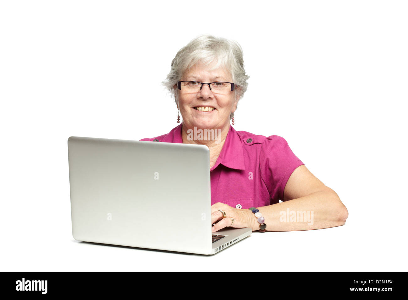 Ältere Frau mit Laptop, während lächelnd, auf weißem Hintergrund Stockfoto
