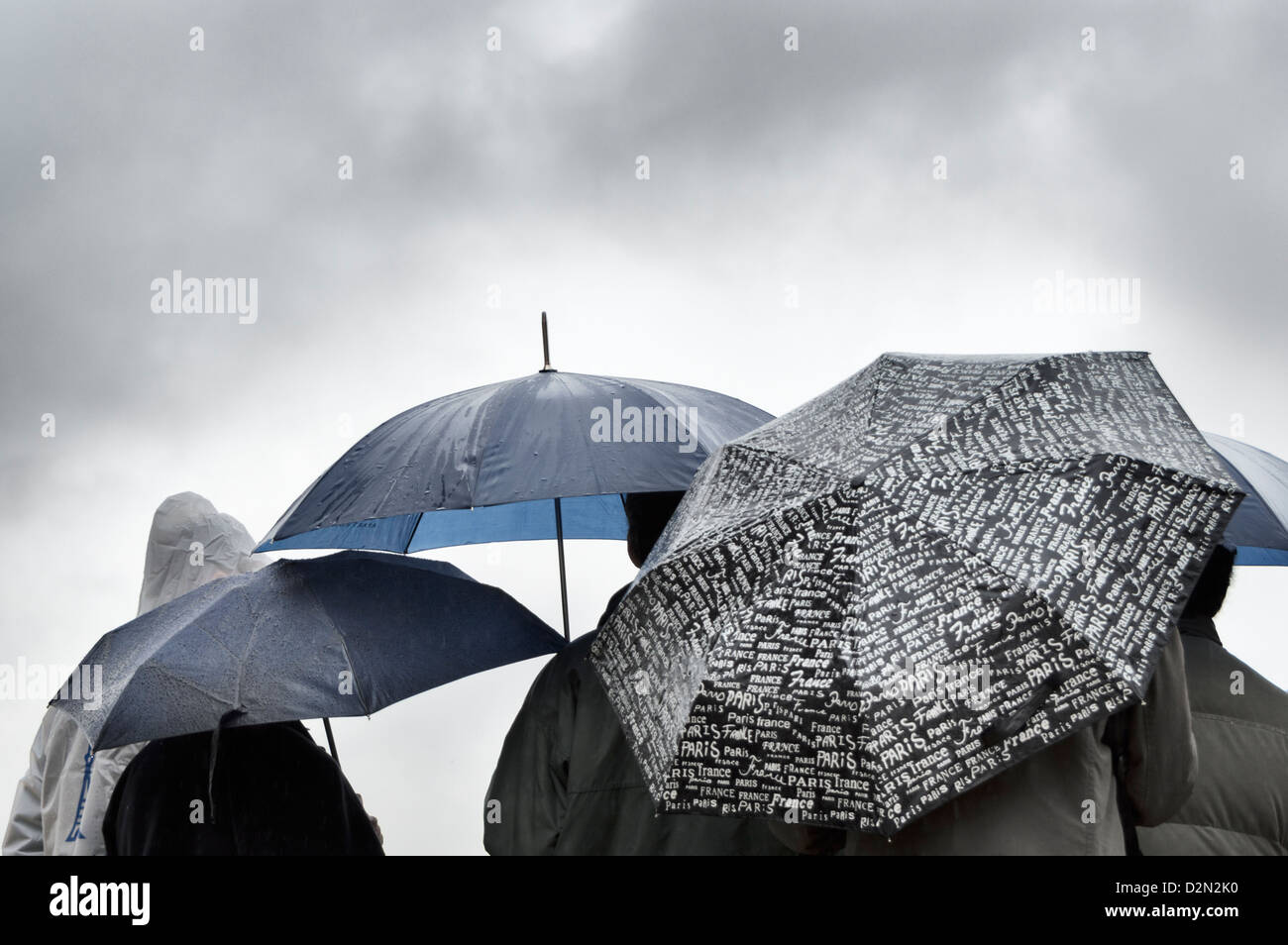 Eine Gruppe von Menschen, die Zuflucht vor dem Regen unter Sonnenschirmen in Paris Stockfoto