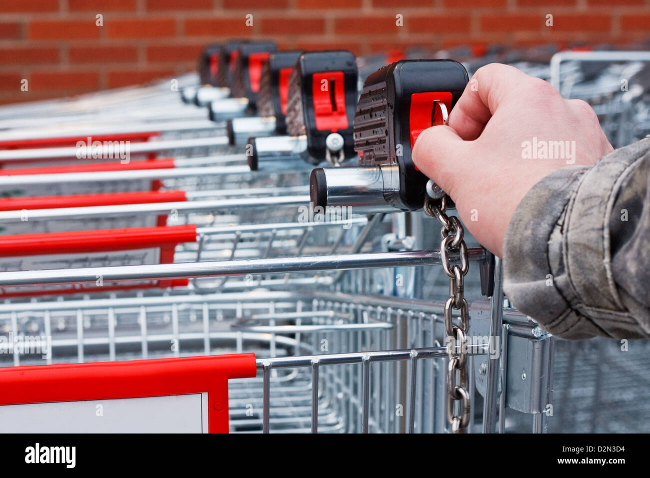 Einfügen von Münz- oder token in Einkaufswagen im Supermarkt Stockfoto