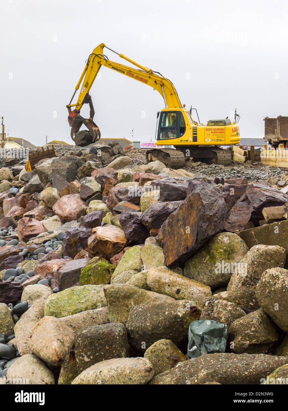 Eine mechanische Digger wird verwendet, um die Wartung und die Reparatur des Meer Abwehr auf dem Kiesel Ridge auf Westward Ho zu verpflichten! Strand. Devon, England. Stockfoto