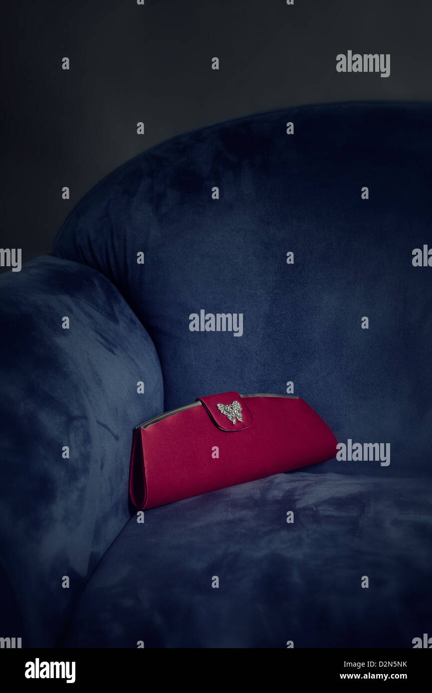 eine rote Handtasche liegen auf einem blauen Sessel Stockfoto