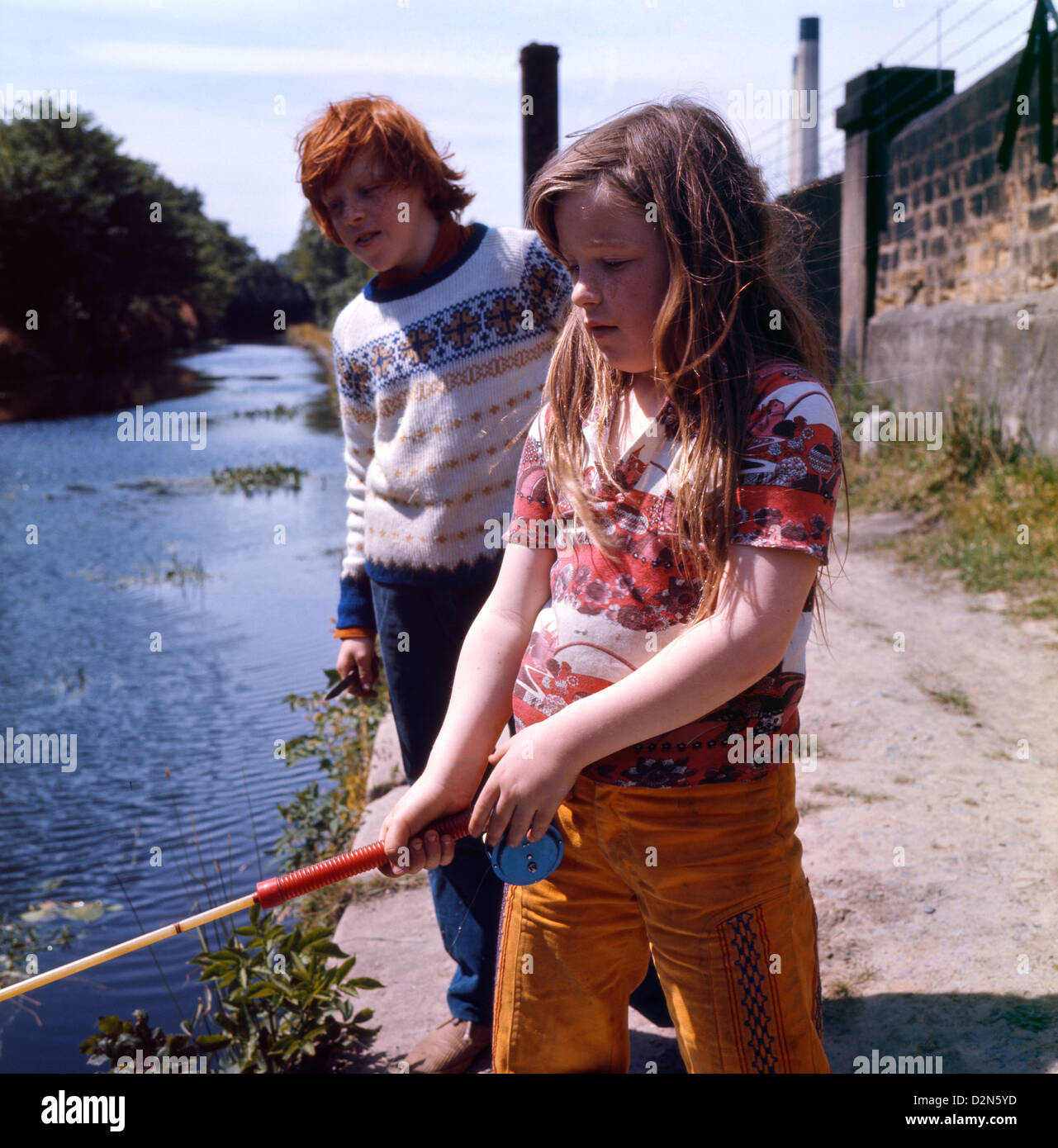 Vintage 1970er britische Kinder Foto eines rothaarigen Mädchens, das draußen mit einem Jungen angeln in einem Leeds Kanal Yorkshire England UK 1974 Großbritannien KATHY DEWITT Stockfoto