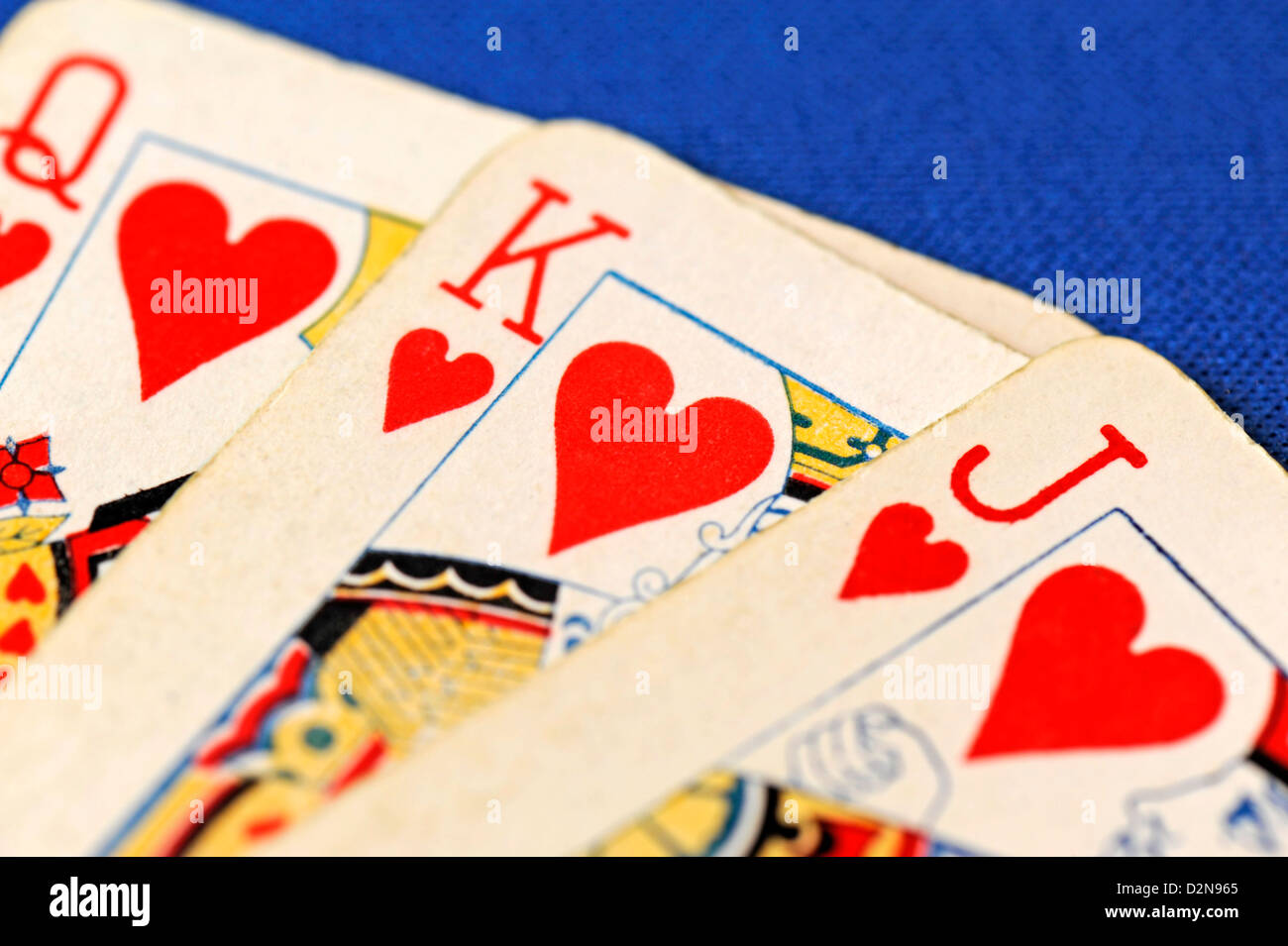 Nahaufnahme von drei Spielkarten - Bube, Dame und Jack of Hearts auf blauem Hintergrund Stockfoto