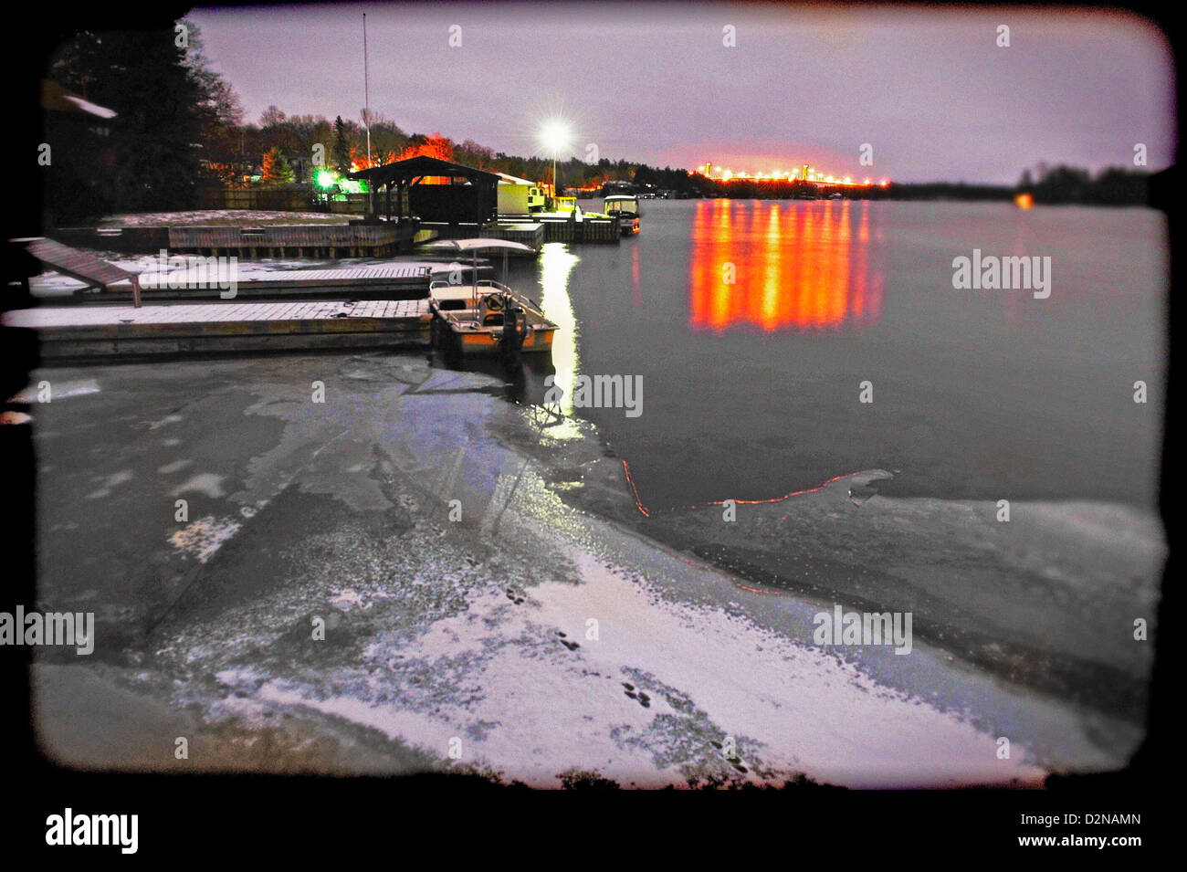1000 Inseln Brücke in Orange von den Ufern des Ivy Lea im Winter mit Eis auf dem Fluss St. Laurence beleuchtet Stockfoto