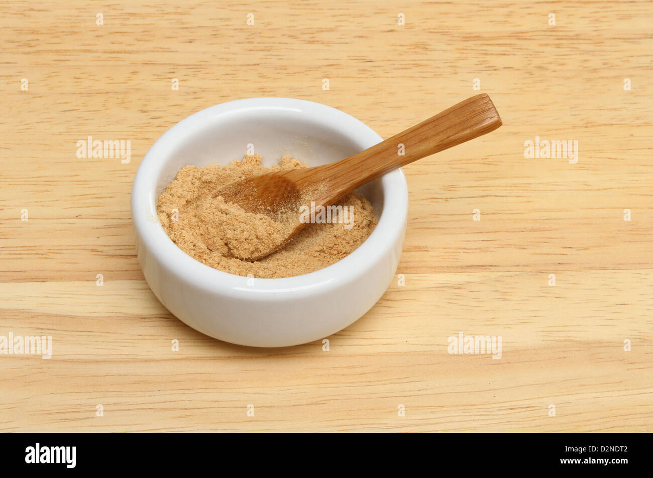 Gemahlener Ingwer in ein Töpfchen auf einem Holzbrett Stockfoto