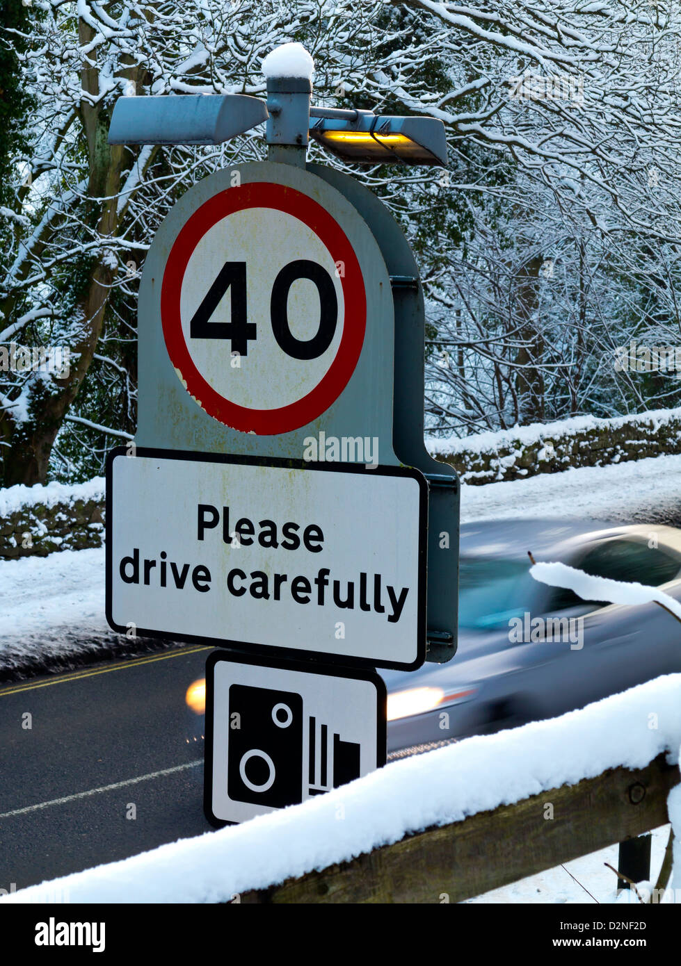 40 km/h und Bitte fahren Sie vorsichtig melden mit Geschwindigkeit Kamera Warnsymbol Winter unterwegs mit dem Auto hinter Derbyshire UK Stockfoto