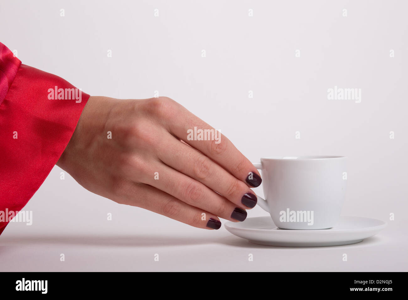 Eine Frau trägt ein rotes Gewand ist für eine Tasse Espresso am Morgen weiß reaching out Stockfoto