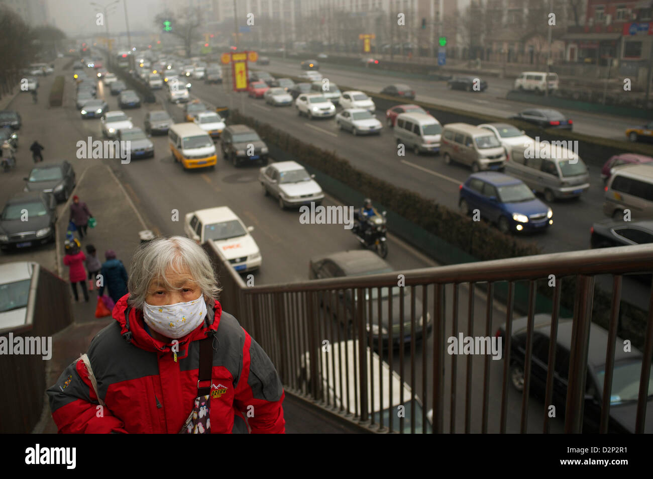Eine ältere Frau trägt eine Maske auf eine Sky-Brücke in dicker Nebel in Peking, China. 30. Januar 2013 Stockfoto