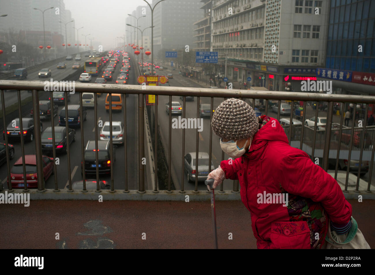 Eine ältere Frau trägt eine Maske auf eine Überführung in dicker Nebel in Peking, China. 30. Januar 2013 Stockfoto