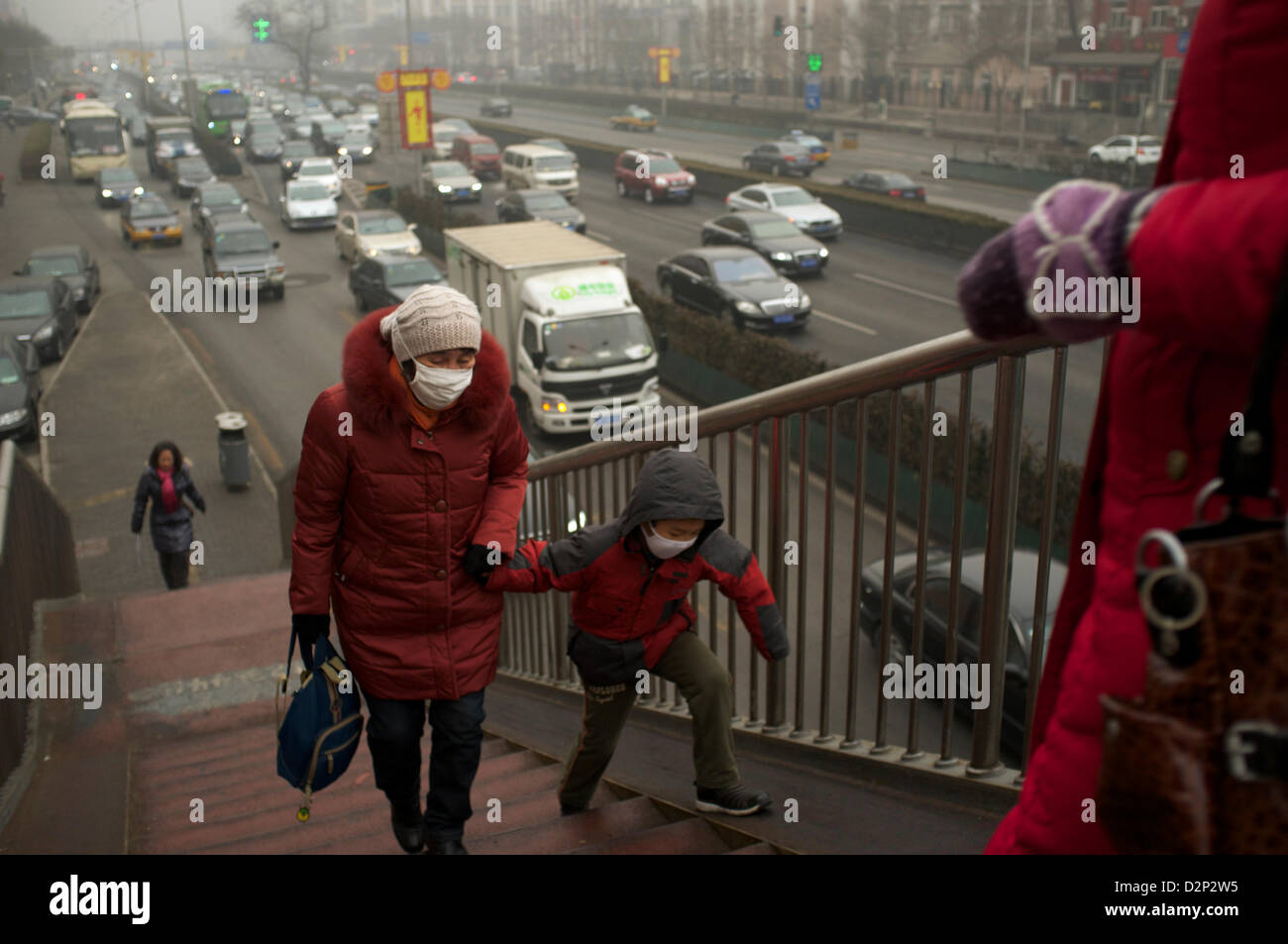 Fußgänger tragen Masken auf einer Überführung in dicker Nebel in Peking, China. 30. Januar 2013 Stockfoto