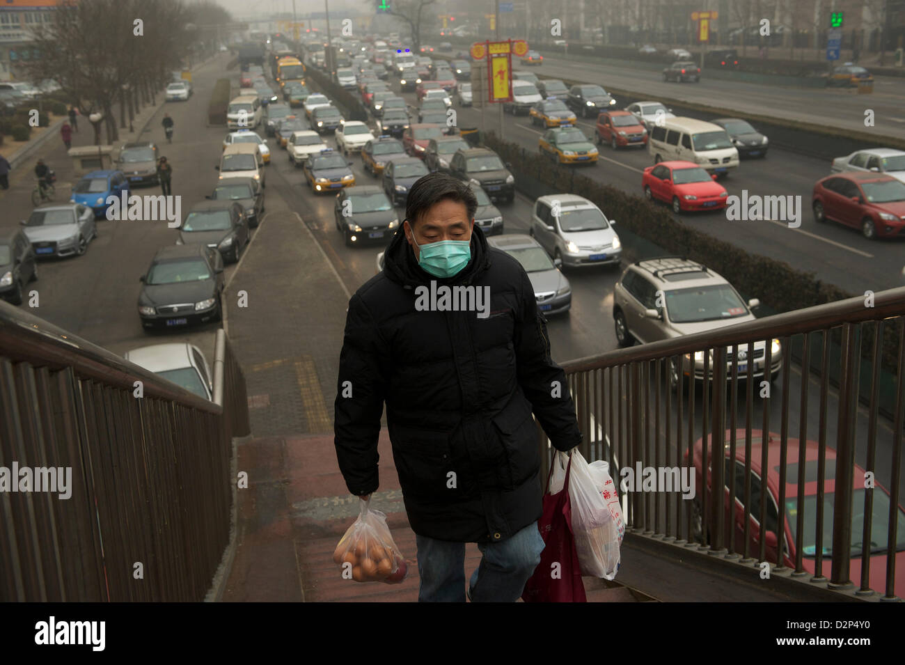 Ein Mann mit einer Maske vorbei an stark befahrenen in dicker Nebel in Peking, China. 30. Januar 2013 Stockfoto