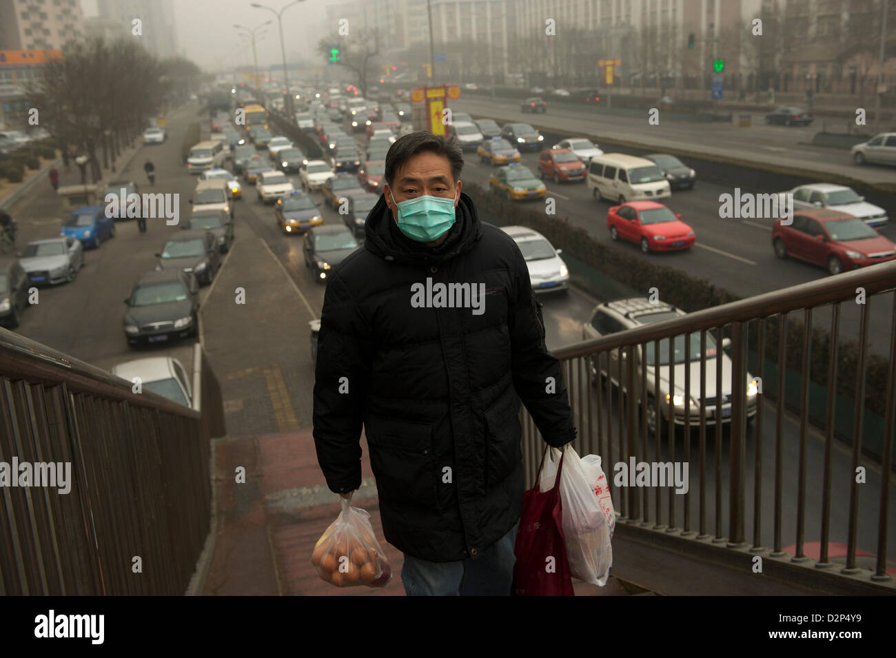Ein Mann trägt eine Maske vorbei an stark befahrenen in dicker Nebel in Peking, China. 30. Januar 2013 Stockfoto