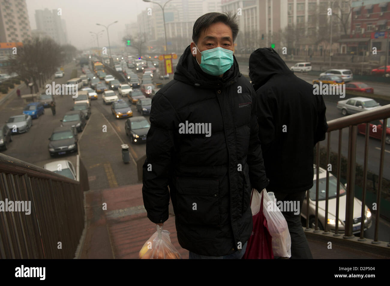 Ein Mann trägt eine Maske vorbei an stark befahrenen in dicker Nebel in Peking, China. 30. Januar 2013 Stockfoto
