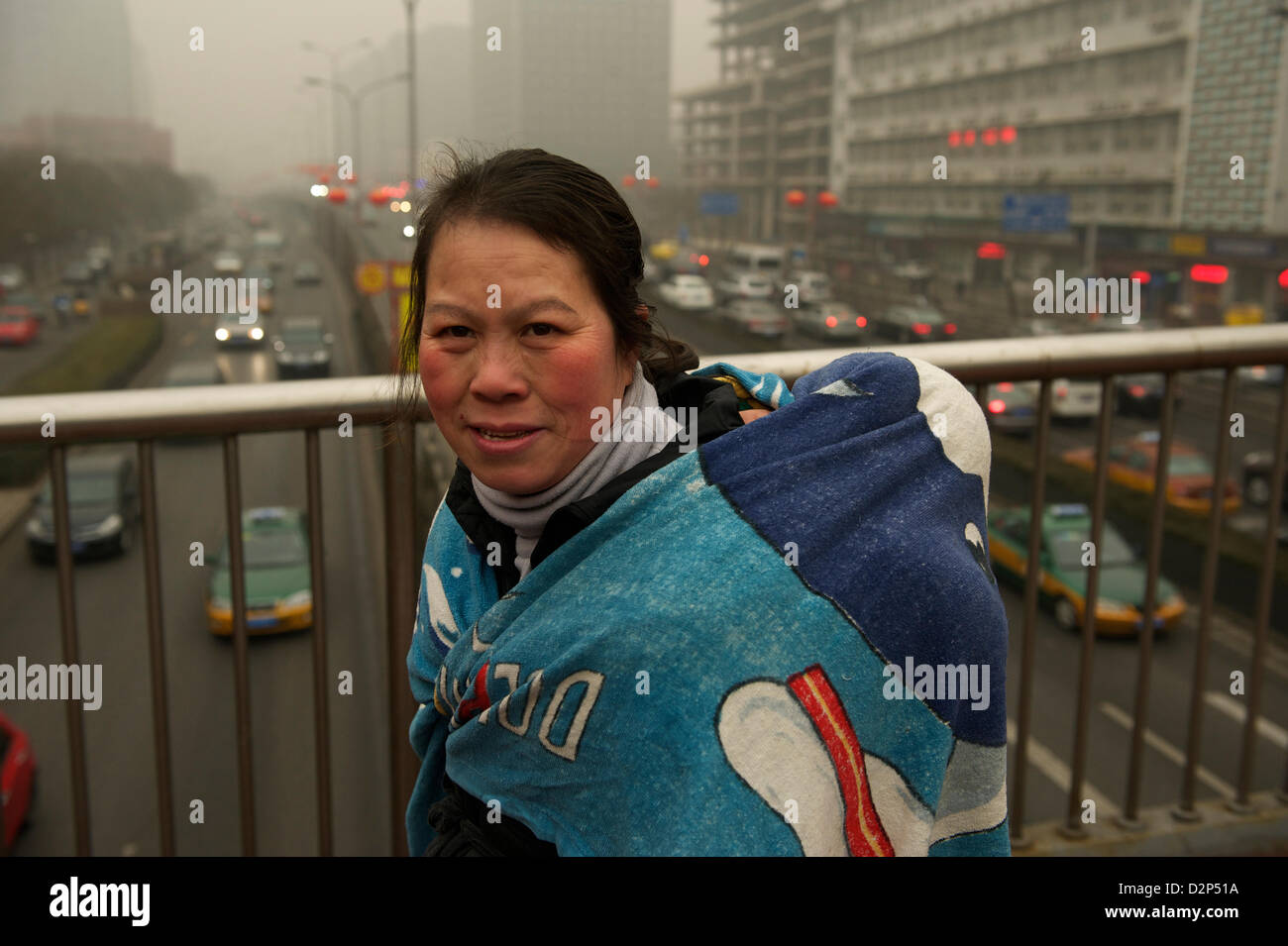 Eine Frau deckt ein Baby mit einer Decke in dicker Nebel in Peking, China. 30. Januar 2013 Stockfoto